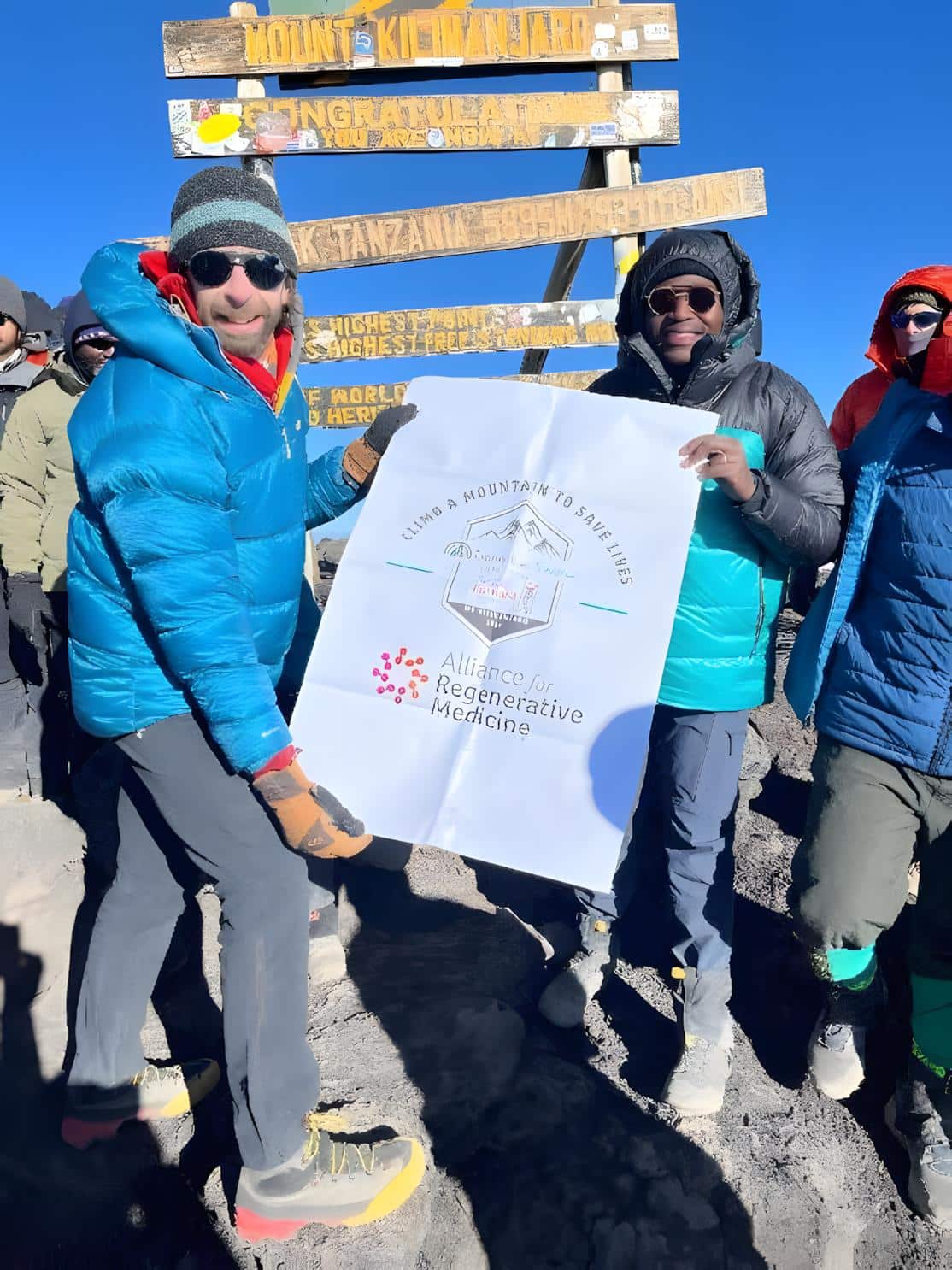 Climbers at Mount Kilimanjaro displaying Alliance for Regenerative Medicine banner, raising awareness for regenerative therapies